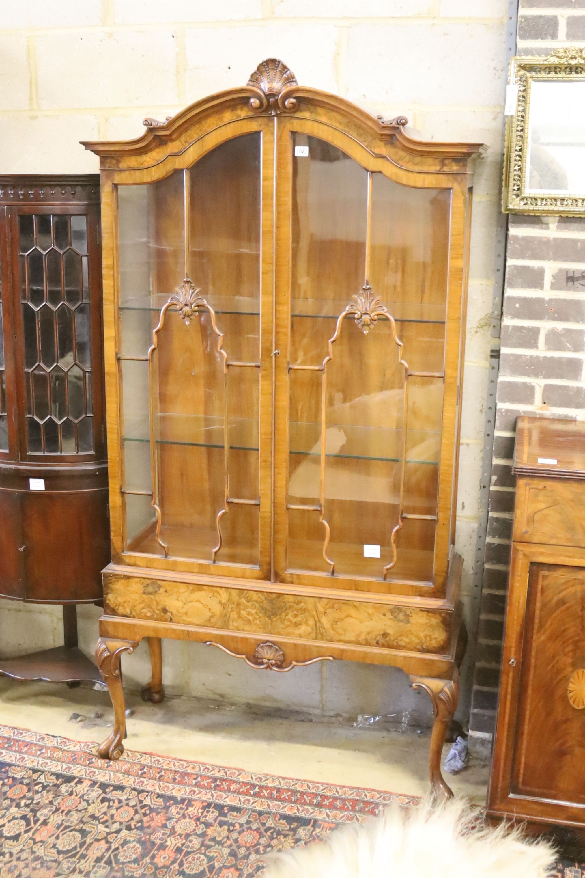 A George I style figured walnut display cabinet with glazed doors on cabriole supports and scrolled legs, width 100cm, depth 40cm, height 192cm